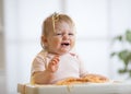 Cute messy baby crying while eating pasta at home Royalty Free Stock Photo