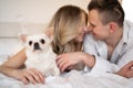 Cute middle aged european couple with chihuahua dog in the bedroom on the bed. Man and woman with domestic dog cozy