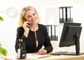 Cute middle-aged office worker talking on cell phone in office