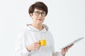 Cute middle-aged woman in casual clothes is looking online stores using a tablet and holding small yellow cup of coffee Royalty Free Stock Photo