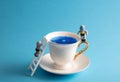 Cute miniatures of astronauts climb on  white mug with blue liquid on  blue background. Cute postcard for space day Royalty Free Stock Photo