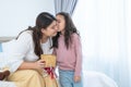 Cute mixed race child daughter, Caucasian and Asian, kissing and giving gift box to young mother for mother's day Royalty Free Stock Photo