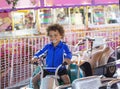 Cute mixed race little boy enjoying a ride on a fun carnival carousel ride.