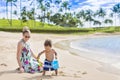 Cute mixed race little boy playing in the sand the beach with his mother Royalty Free Stock Photo