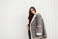 Cute model of a beautiful young woman in a vintage checkered jacket with fur in a warm stylish knitted sweater stands on the
