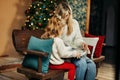 Cute mom and daughter are looking through a family photo album on Christmas Eve, spending time together by the fireplace Royalty Free Stock Photo