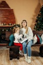 Cute mom and daughter are looking through a family photo album on Christmas Eve, spending time together by the fireplace Royalty Free Stock Photo