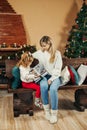 Cute mom and daughter are looking through a family photo album on Christmas Eve, spending time together by the fireplace Royalty Free Stock Photo