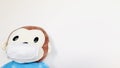 Cute monkey soft toy wearing a face mask with pale white background.