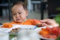 Cute 5-6 month asian baby girl doesn `t want to eat watermelon