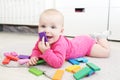 Cute 6 month baby girl plays wooden multicolored meccano at home