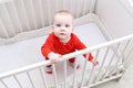 Cute 6 month baby standing in white bed