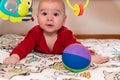 Cute 6 months little baby boy with curiosity expression on his face surrounded by colourful toys Royalty Free Stock Photo