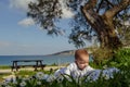 Cute 4 months old baby boy having a tummy time under the tree and sea in the background Royalty Free Stock Photo