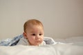 Cute 4 months old baby boy having tummy time on white quilt covered with blue blanket Royalty Free Stock Photo