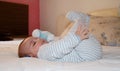 Cute 4 months old baby boy lying on bed and playing with his legs Royalty Free Stock Photo