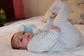 Cute 4 months old baby boy lying on bed and playing with his legs Royalty Free Stock Photo