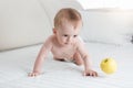 Cute 10 months old baby playing with yellow apple on bed Royalty Free Stock Photo