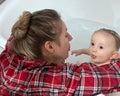 A cute mother is bathing a baby boy in clear water in a bathtub