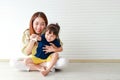 Cute mother and daughter Hugging and teasing each other sitting on the floor of the house.