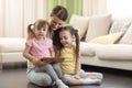 Cute mother with her 2 years old little daughter and 5 years old daughter playing with digital tablet at home Royalty Free Stock Photo