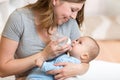 Cute mother at home feeding baby with a milk bottle Royalty Free Stock Photo