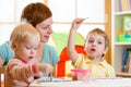 Cute mother teaching her kids to paint