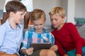 Cute multiracial elementary schoolboys looking at digital tablet while sitting on couch in school