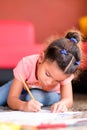 Cute multiracial small girl drawing on a coloring book