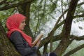 Muslim female student reading a book in nature, outdoor