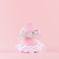 Cute naivety easter background with pink egg with grey bow in white nest on pastel pink backdrop, square. Royalty Free Stock Photo