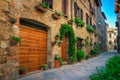 Cute narrow street decorated with flowers in Pienza, Tuscany, Italy