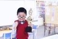 Cute nerd boy holding trophy at library Royalty Free Stock Photo