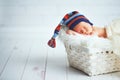 Cute newborn baby in blue knit cap sleeping in basket Royalty Free Stock Photo