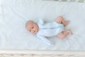 Cute newborn baby boy lying on the back of the crib on the cotton bed at home before going to bed, baby week, the concept of birth Royalty Free Stock Photo