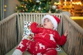 Cute newborn baby boy next to a Christmas tree with festive decoration and ferry lights for New Year celebration