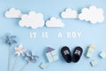 Cute newborn baby boy shoes with festive decoration over blue background. Baby shower, birthday, invitation or greeting card Royalty Free Stock Photo