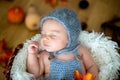 Cute newborn baby boy, sleeping with autumn leaves in a basket a Royalty Free Stock Photo