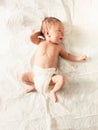 Cute newborn baby in diapers lying on white sheets on bed Royalty Free Stock Photo