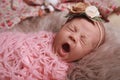 Cute baby girl with floral headband lying on fuzzy rug, closeup