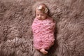 Cute baby girl with floral headband lying on fuzzy rug, top view
