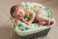 Cute newborn baby girl in a pink knit romper sleeping on a felted green blanket in a basket Royalty Free Stock Photo