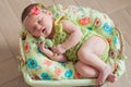 Cute newborn baby girl in a pink knit romper sleeping on a felted green blanket in a basket Royalty Free Stock Photo