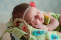 Cute newborn baby girl in a pink knit romper sleeping on a felted green blanket in a basket Royalty Free Stock Photo