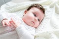 Cute newborn baby girl in romper suit lying on woolen blanket