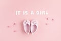 Cute newborn baby girl shoes with festive decoration over pink background. Baby shower, birthday, invitation or greeting card Royalty Free Stock Photo