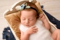 A cute newborn baby girl sleeps in a wooden crib on a brown pillow. Royalty Free Stock Photo