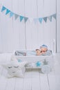 cute newborn baby in hat sleeping in wooden baby cot with star pillow