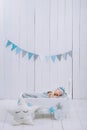 cute newborn baby in hat sleeping in wooden baby cot with star pillow