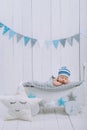 cute newborn baby in hat sleeping in wooden baby cot with star pillow